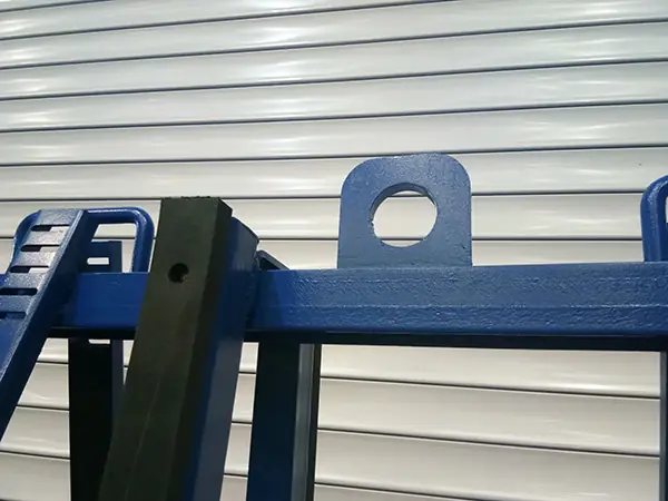 Close-up of lifting lug and protective pads on a blue slab transport rack