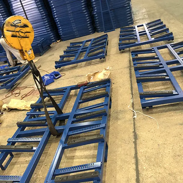Blue steel rack bases on a workshop floor while one frame is being lifted